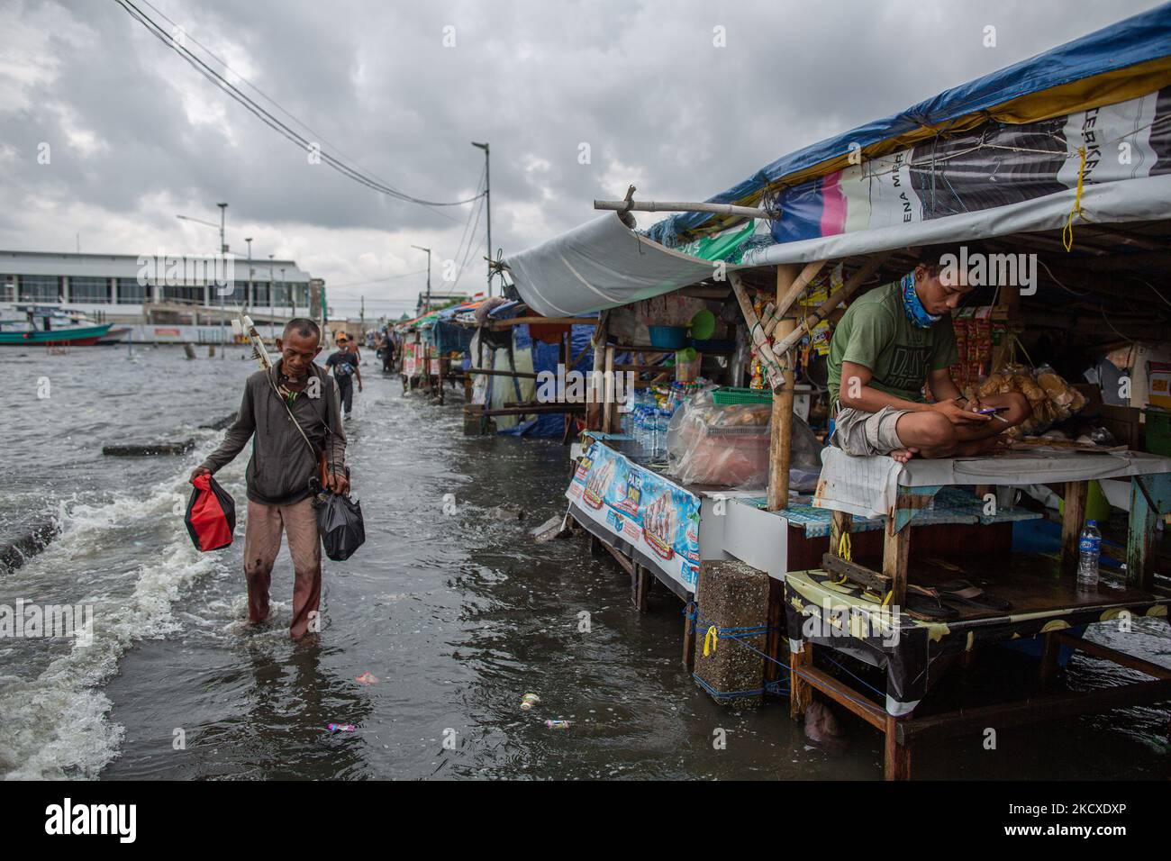 Les résidents passent par un arrêt alimentaire pendant les vagues de marée dans la zone côtière de Jakarta, Muara Angke, le 7 décembre 2021. Les autorités locales ont prédit que des marées et des vents violents frapperont la région de la baie de Jakarta et le nord de W. Java du 6 au 9 décembre, ce qui provoquerait l'immersion de la zone côtière de la capitale et endommagera les maisons. Les inondations causées par le débordement d'eau de mer ont submergé 15 unités de quartier dans le nord de Jakarta et l'ouest de Jakarta. (Photo par Afriadi Hikmal/NurPhoto) Banque D'Images
