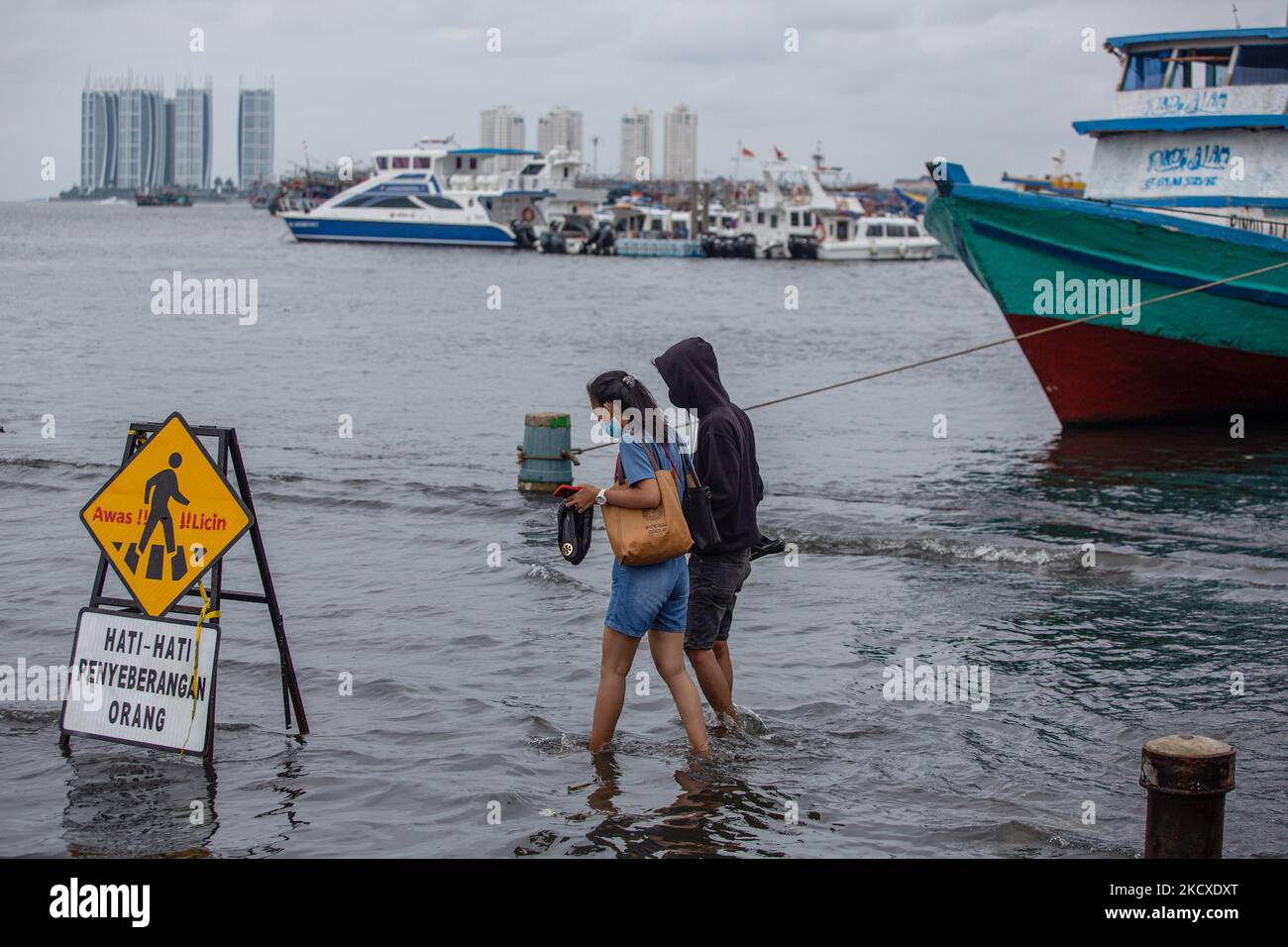 Personnes marchant au port de Muara Angke pendant les vagues de marée dans la zone côtière de Jakarta, Muara Angke, le 7 décembre 2021. Les autorités locales ont prédit que des marées et des vents violents frapperont la région de la baie de Jakarta et le nord de W. Java du 6 au 9 décembre, ce qui provoquerait l'immersion de la zone côtière de la capitale et endommagera les maisons. Les inondations causées par le débordement d'eau de mer ont submergé 15 unités de quartier dans le nord de Jakarta et l'ouest de Jakarta. (Photo par Afriadi Hikmal/NurPhoto) Banque D'Images