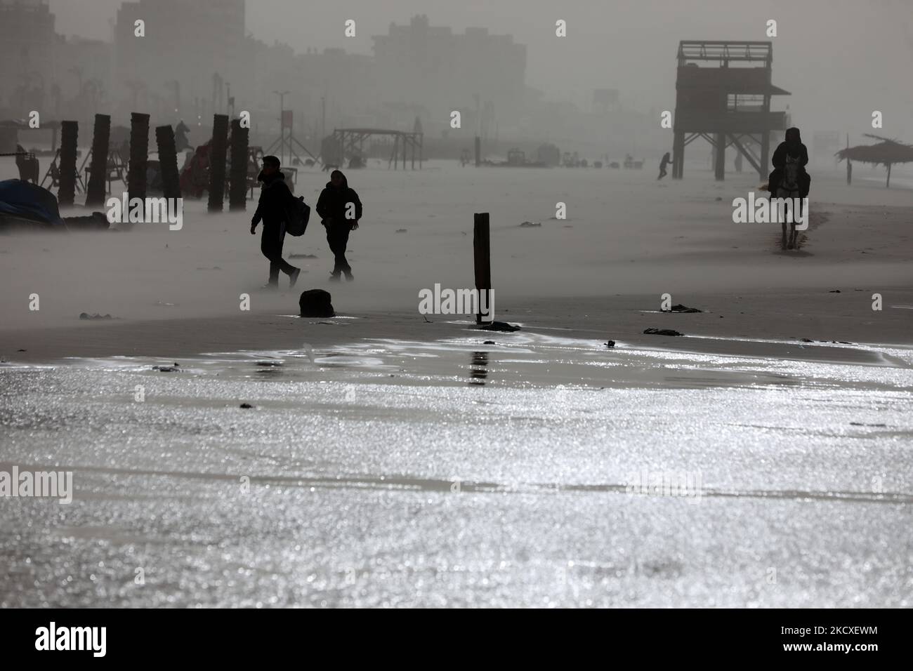 Les Palestiniens marchent sur les rives de la mer Méditerranée lors d'une tempête de poussière dans la ville de Gaza, 8 décembre 2021. (Photo de Majdi Fathi/NurPhoto) Banque D'Images