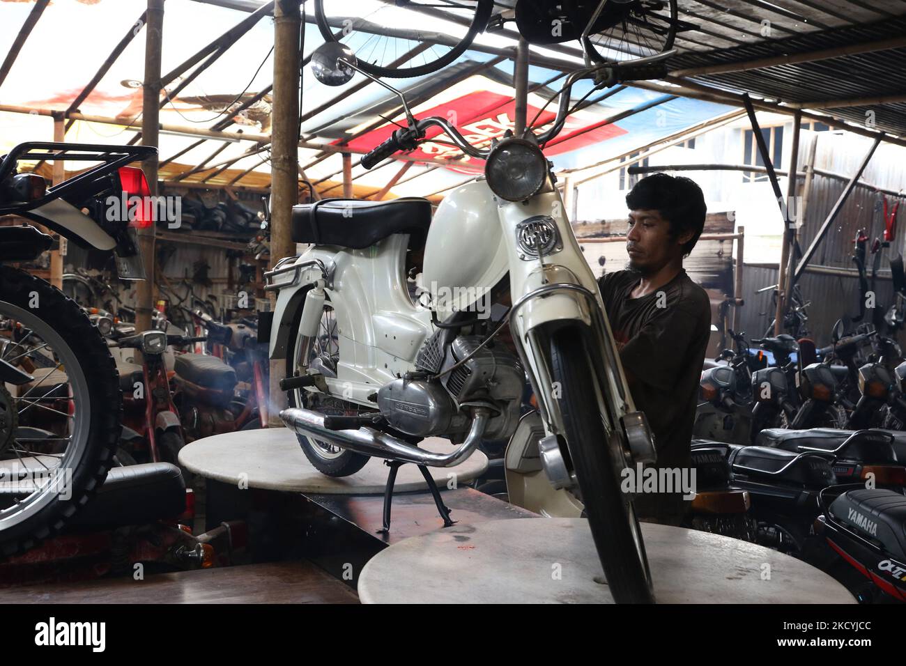 Les travailleurs remplacent les pièces de motocyclettes anciennes qui sont  en cours de restauration à l'ancienne galerie automobile de Pondok Cabe,  Tangerang, 29 décembre 2021. Les motos anciennes de 1950s à 1980s