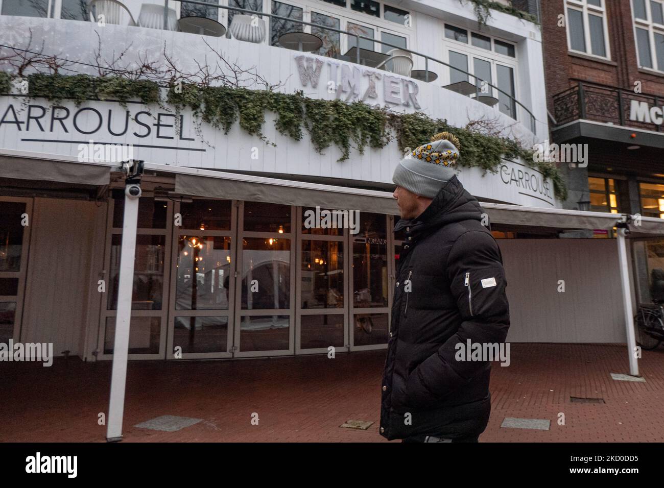 Un homme passe devant un restaurant fermé à Eindhoven pendant le confinement. Les pays-Bas ont en partie renforcé les mesures de confinement à partir du 15 janvier, après le confinement de 4 semaines, avec l'ouverture de tous les magasins non essentiels avec des heures de travail limitées, des universités, des coiffeurs et des gymnases, ainsi qu'une capacité réduite, mais les cafés, bars et restaurants resteront fermés jusqu'au 25 janvier. une action contre laquelle de nombreux propriétaires de magasins sont opposés. La vie quotidienne à Eindhoven tandis que les gens marchent dans le quartier commercial du centre ou attendent en ligne pour recevoir des produits des magasins par clic et de collecte Banque D'Images