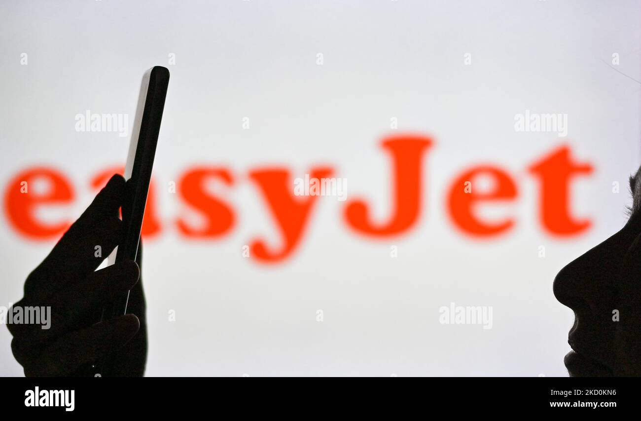 Image d'une femme tenant un téléphone portable devant le logo easyJet affiché sur un écran d'ordinateur. Mardi, 12 janvier 2021, à Edmonton, en Alberta, Canada. (Photo par Artur Widak/NurPhoto) Banque D'Images