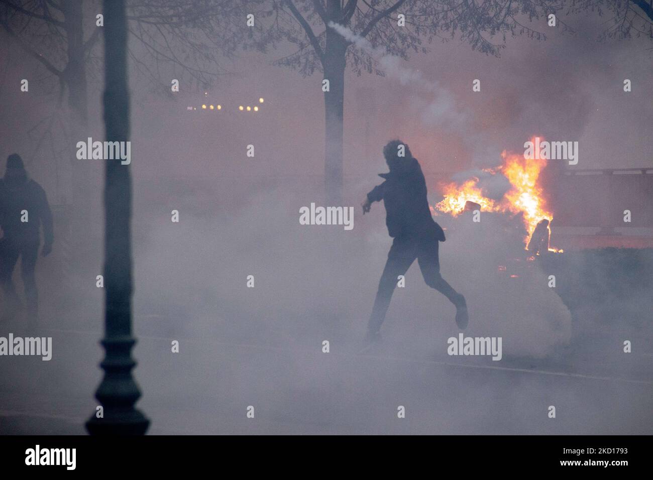 Le démonstrateur se jette dans le gaz lacrymogène de la police pendant qu'un feu sur une barricade routière est en feu. Des milliers de personnes protestent lors de la manifestation européenne pour la démocratie contre les mesures liées à Covid, comme le pass de santé et les restrictions de la COVID. Les émeutes ont commencé à éclater et la police a déclenché des gaz lacrymogènes et des canons à eau alors que la manifestation est devenue violente. Les gens prennent part à une manifestation contre les mesures sanitaires à Bruxelles comme le COVID Health Pass, le code QR, les masques faciaux et la vaccination obligatoire, en utilisant comme slogan principal et sur les bannières le mot liberté traduit comme liberté. Les autorités l'ont estimé autour Banque D'Images
