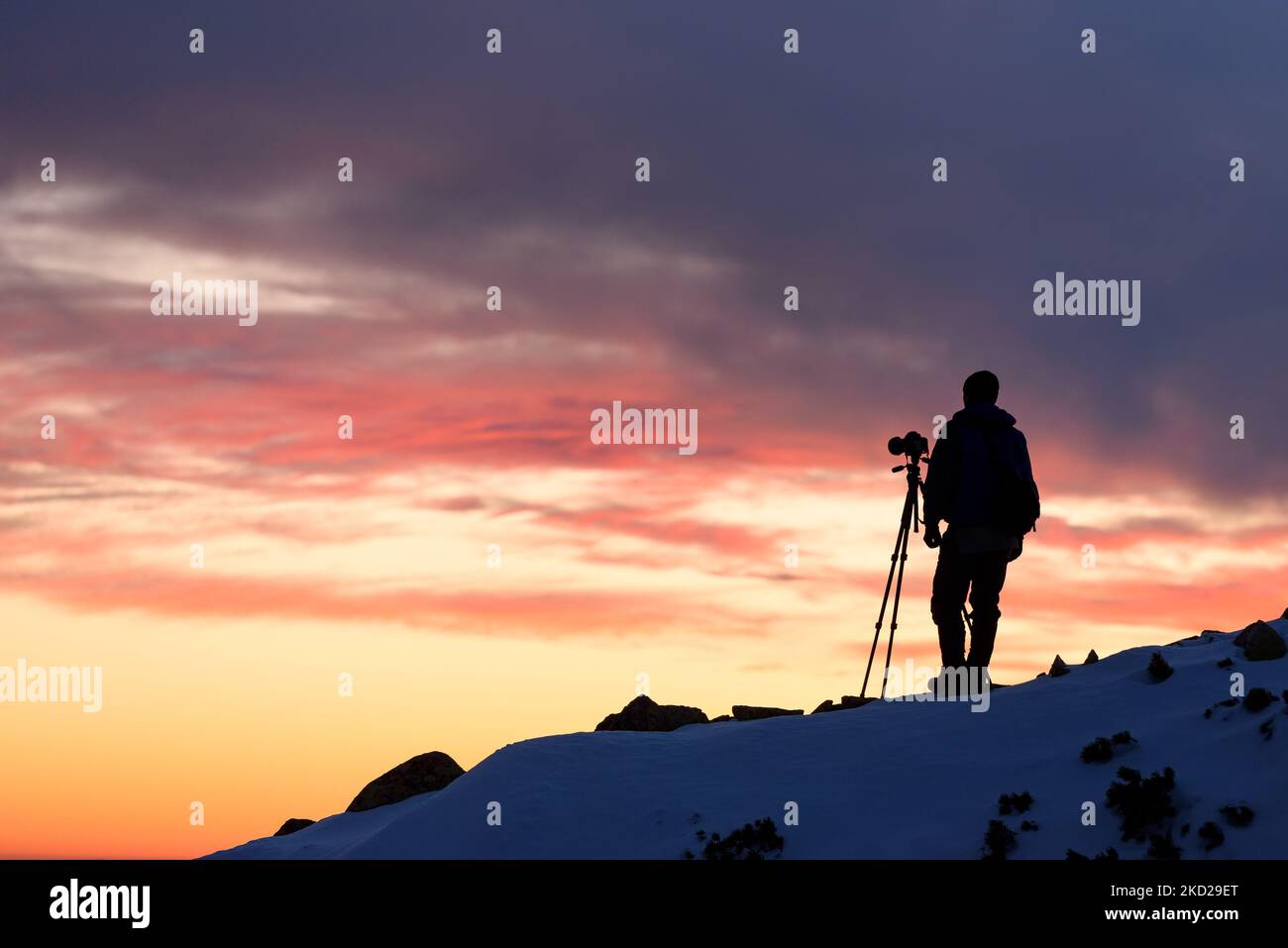 Photographe paysagiste avec un trépied qui photographie dans les montagnes au coucher du soleil Banque D'Images