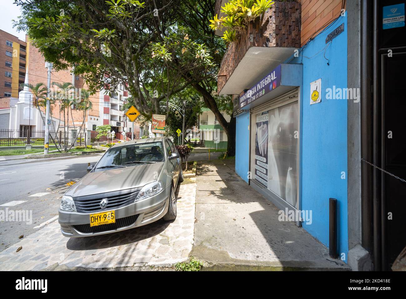 Medellin, Antioquia, Colombie - 2 juin 2022: Voiture grise garée dans la rue résidentielle de quartier et trottoir avec Maison bleue Banque D'Images