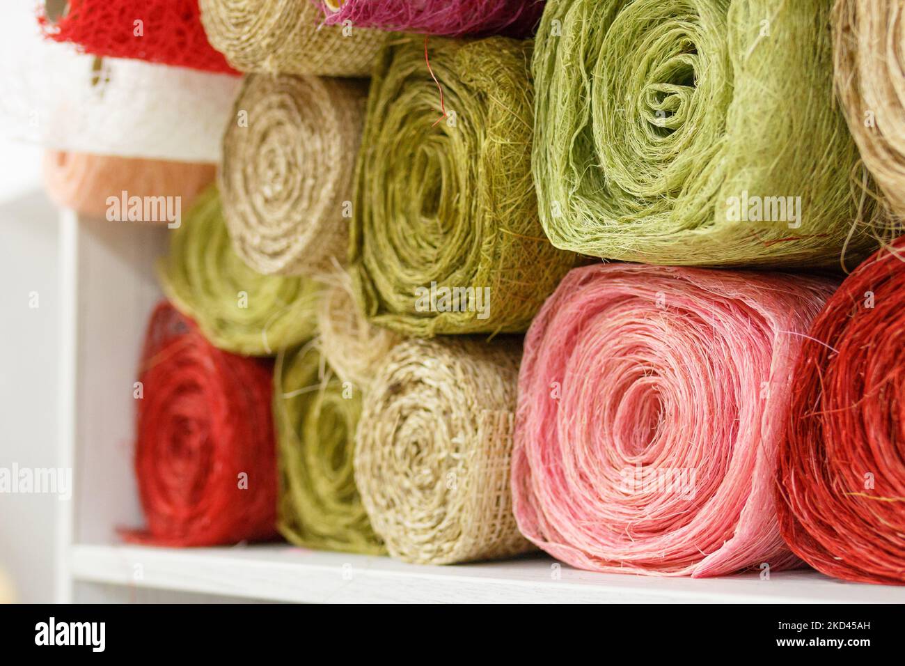 Rouleaux de tissu pour la couture. Fils multicolores de couleur verte, rose, rouge. Outils de couture. Fils, tricots, crochet, soie, lin, synthétiques à la main Banque D'Images