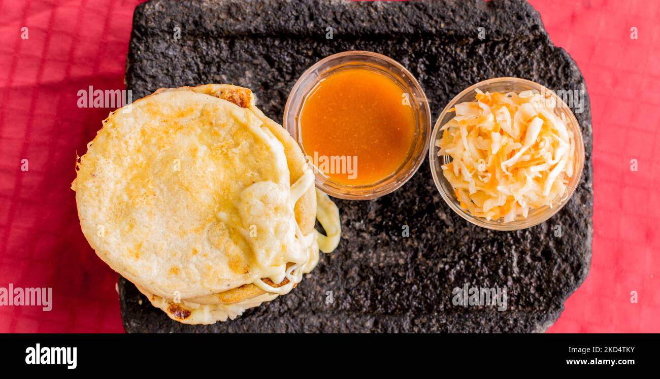 Plat salvadorien typique, marionnettes au fromage avec sauce au chou et à la tomate. Marionnettes au riz et au maïs farcies au fromage, aux haricots ou à d'autres ingrédients Banque D'Images