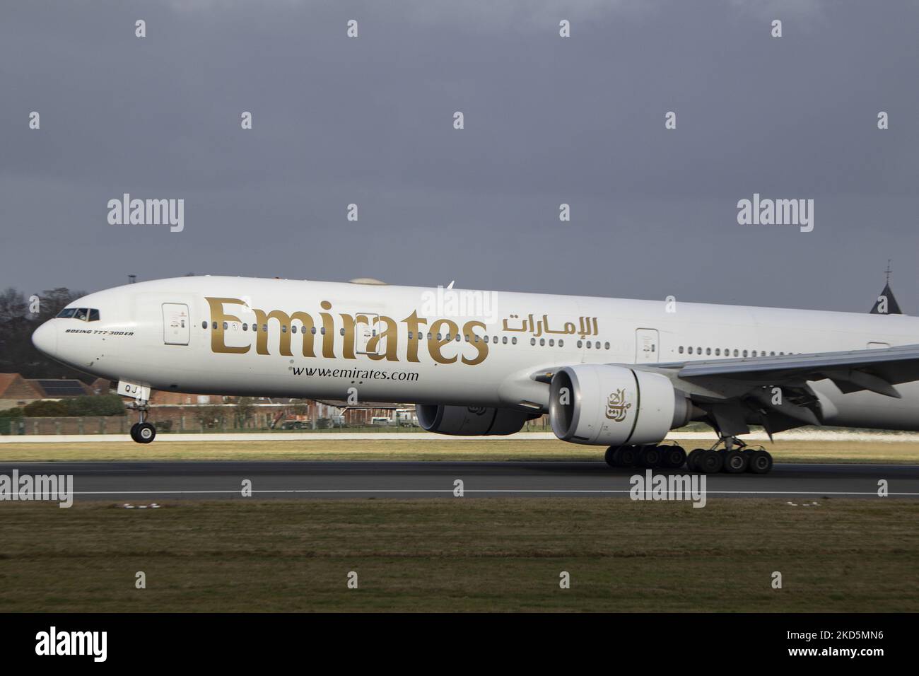 Emirates Boeing 777 comme vu voler et atterrir sur la piste avec la tour de contrôle et les nuages en arrière-plan. Emirates B777 avion comme vu sur l'approche finale vol, atterrissage et le roulement au sol à la capitale belge, l'aéroport de Bruxelles Zaventem BRU. Le Boeing Boeing 777-31HER, un avion de transport de passagers à gros corps moderne et avancé, est immatriculé A6-EQJ et est équipé de 2x GE90 moteurs à réaction. L'avion arrive à la ville européenne en provenance de Dubai DXB, Émirats Arabes Unis. Emirates est la plus grande compagnie aérienne et l'une des deux, porte-drapeau des Émirats arabes Unis. L'industrie de l'aviation et le trafic de passagers Banque D'Images