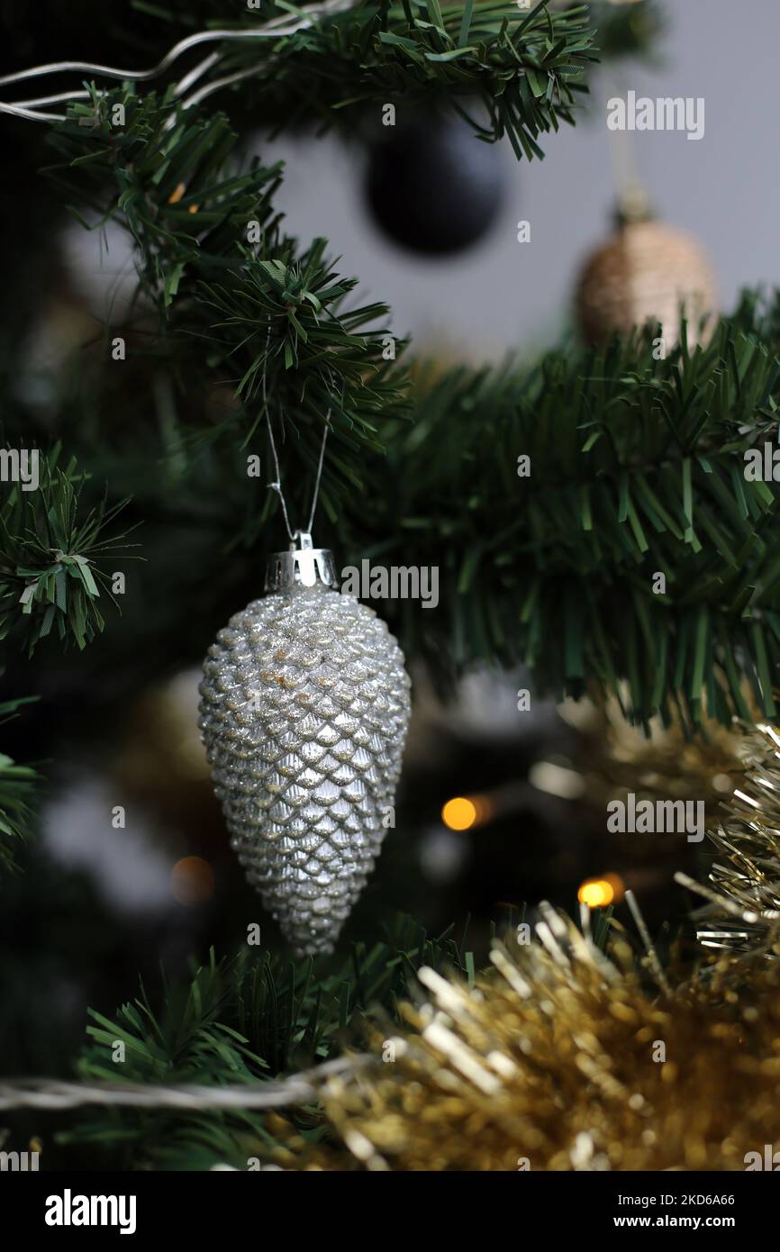 Gros plan d'un sapin de Noël vert avec ornements or, blanc et argent, guirlande dorée et petites lumières décoratives. Arrière-plan gris. Joyeux et heureux Banque D'Images