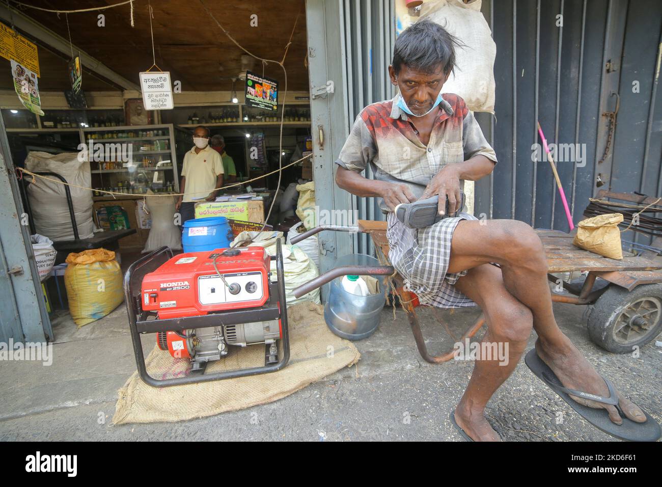 Un employé de salaire quotidien sri-lankais répare une chaussure tandis qu'un générateur électrique fournit de l'électricité à un magasin proche de chez vous en raison d'une coupure de courant à Colombo, au Sri Lanka. 1 avril 2022. (Photo de Thharaka Basnayaka/NurPhoto) Banque D'Images