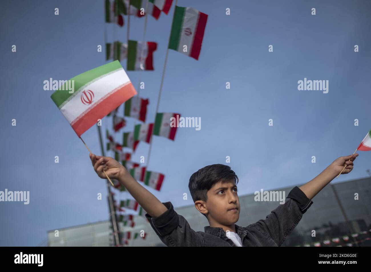 Un garçon iranien fait la vague des drapeaux iraniens dans le jardin du musée d’art dans le nord de Téhéran lors d’une cérémonie marquant la journée nationale iranienne de la République islamique à 1 avril 2022. Le peuple iranien a voté oui lors d'un référendum pour le régime de la République islamique il y a quarante-trois ans. (Photo de Morteza Nikoubazl/NurPhoto) Banque D'Images