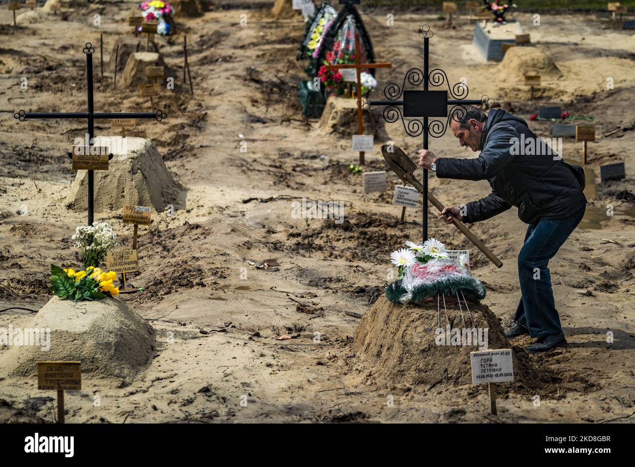 Un homme tient une croix après avoir enterrés un parent tué pendant l'occupation de l'armée russe à Chernihiv. Les cadavres doivent attendre leur destination finale dans une cimenterie, et sont habituellement enterrés par un parent. (Photo de Celestino Arce/NurPhoto) Banque D'Images