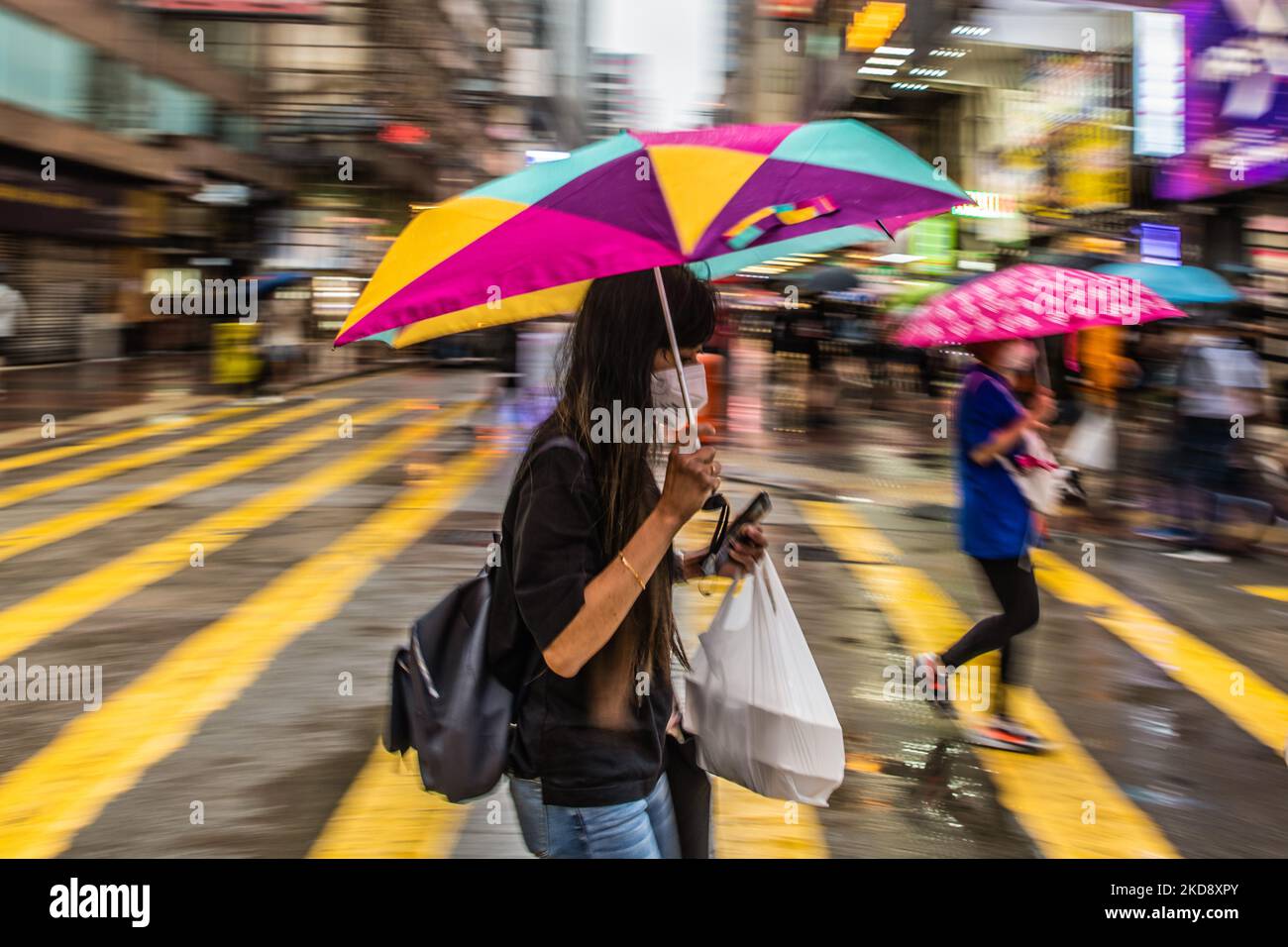 Une dame traverse la rue à Mongkok avec un parapluie coloré. (Photo de Marc Fernandes/NurPhoto) Banque D'Images