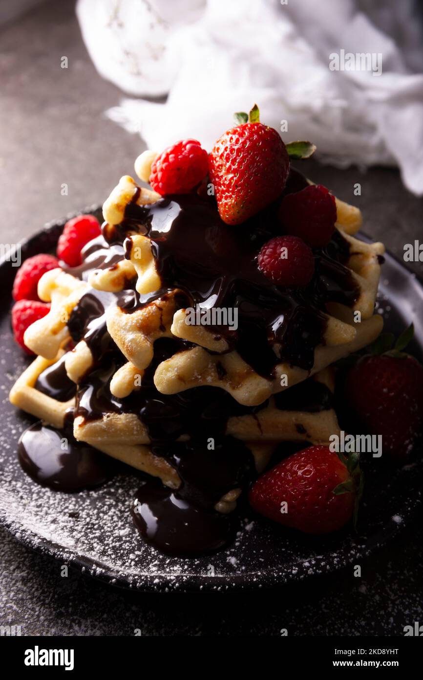 Gaufres fraîches faites maison, fruits et sucre glace enrobés de chocolat fondu. Banque D'Images