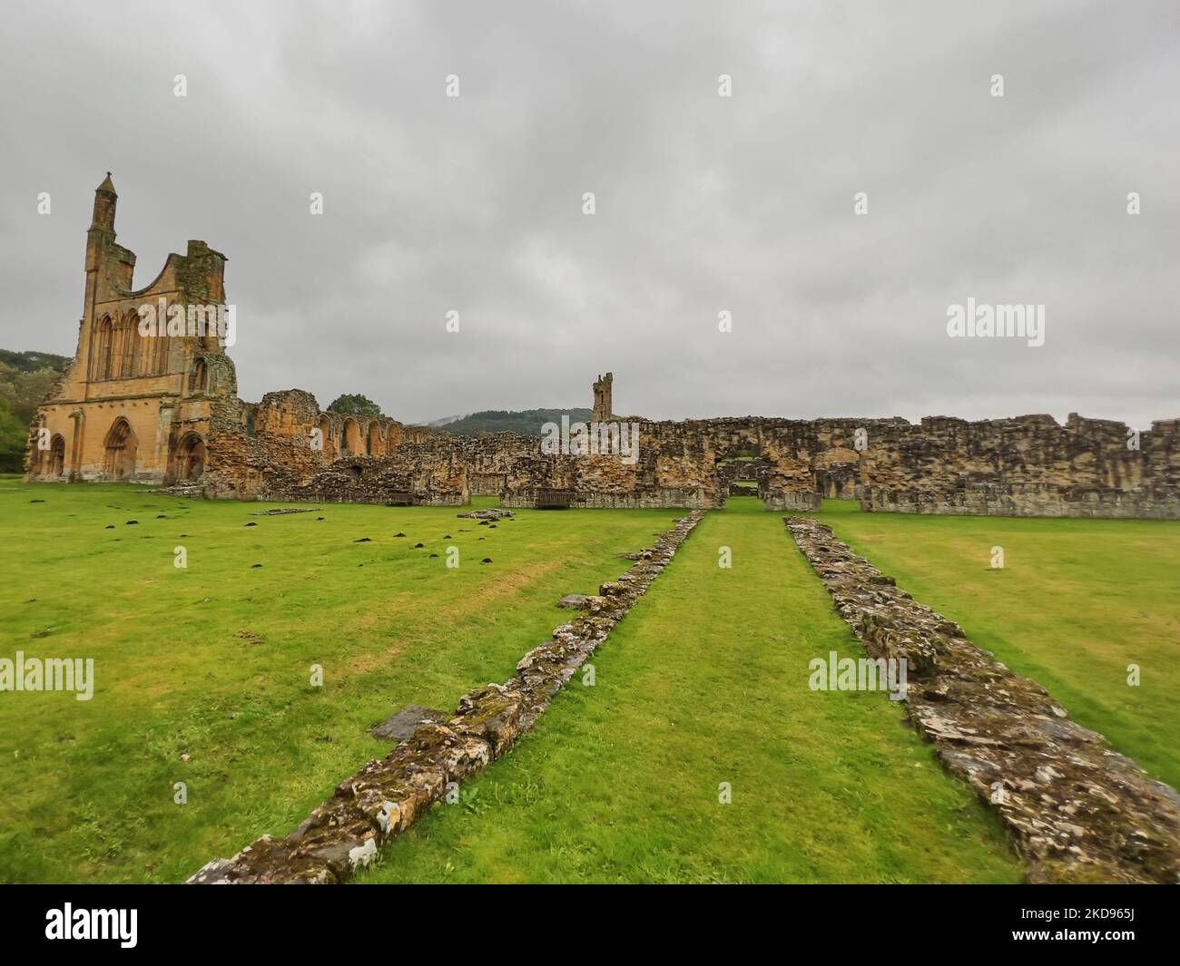 Les ruines de l'abbaye de Byland avec paysage d'herbe et ciel gris nuageux Banque D'Images