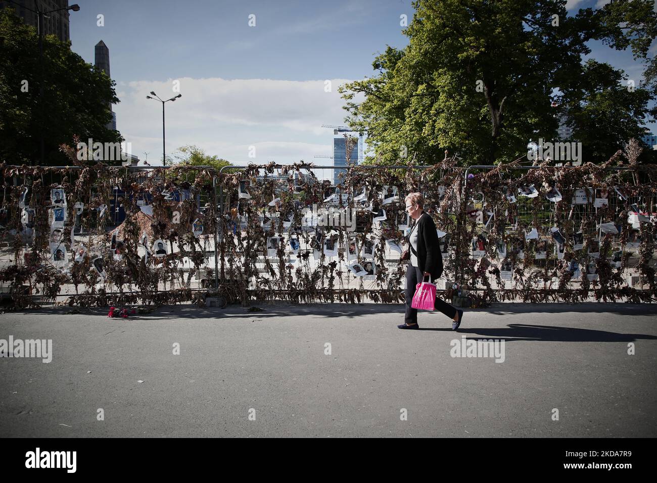 Les gens marchent devant un mur de fleurs avec des photos des victimes ukrainiennes de l'invasion russe à Varsovie, Pologne, le 17 mai 2022. Le conflit a causé environ 8000 mille victimes et plus de 6 millions de redevances dans ce que l'ONU a appelé la plus grande crise humanitaire en Europe depuis les guerres yougoslaves de 1990s. (Photo par STR/NurPhoto) Banque D'Images