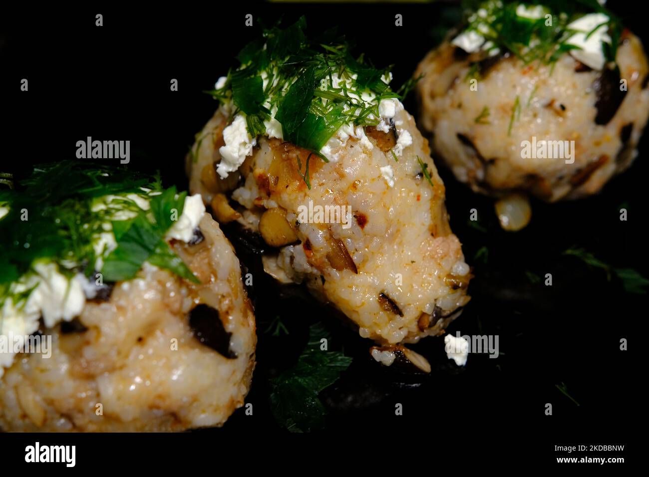 Nourriture japonaise, viande et champignons d'huîtres boule de riz avec vert sur le dessus du fromage sur fond noir. Banque D'Images