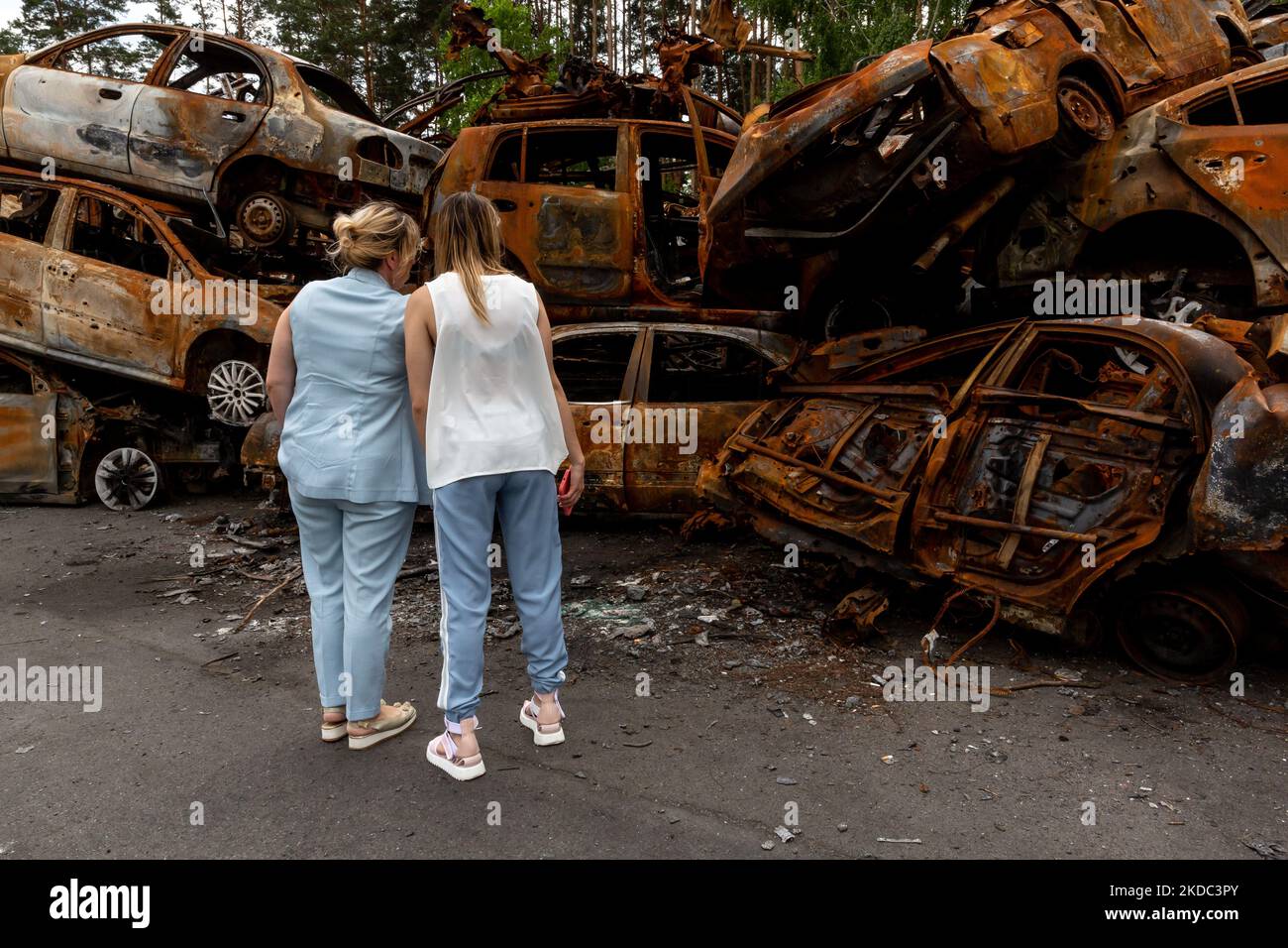 Deux femmes regardent des voitures brûlées sur un parking détruit par bombardement sur 14 juin 2022 à Irpin, en Ukraine. Les voitures ont été récupérées dans la rue et sont stockées temporairement sur un parking public à Irpin. La scène attire l'attention. Alors que la Fédération de Russie a envahi l'Ukraine il y a plus de 3 mois et demi, des combats acharnés se poursuivent dans l'est du pays. Quelques-unes des villes les plus dévastées depuis le début du conflit - Irpin et Bucha - construisent leur chemin vers la normalité. De plus en plus de civils reviennent chez eux et réétablissent leur vie. (Photo par Dominika Zarzycka/NurPhoto) Banque D'Images