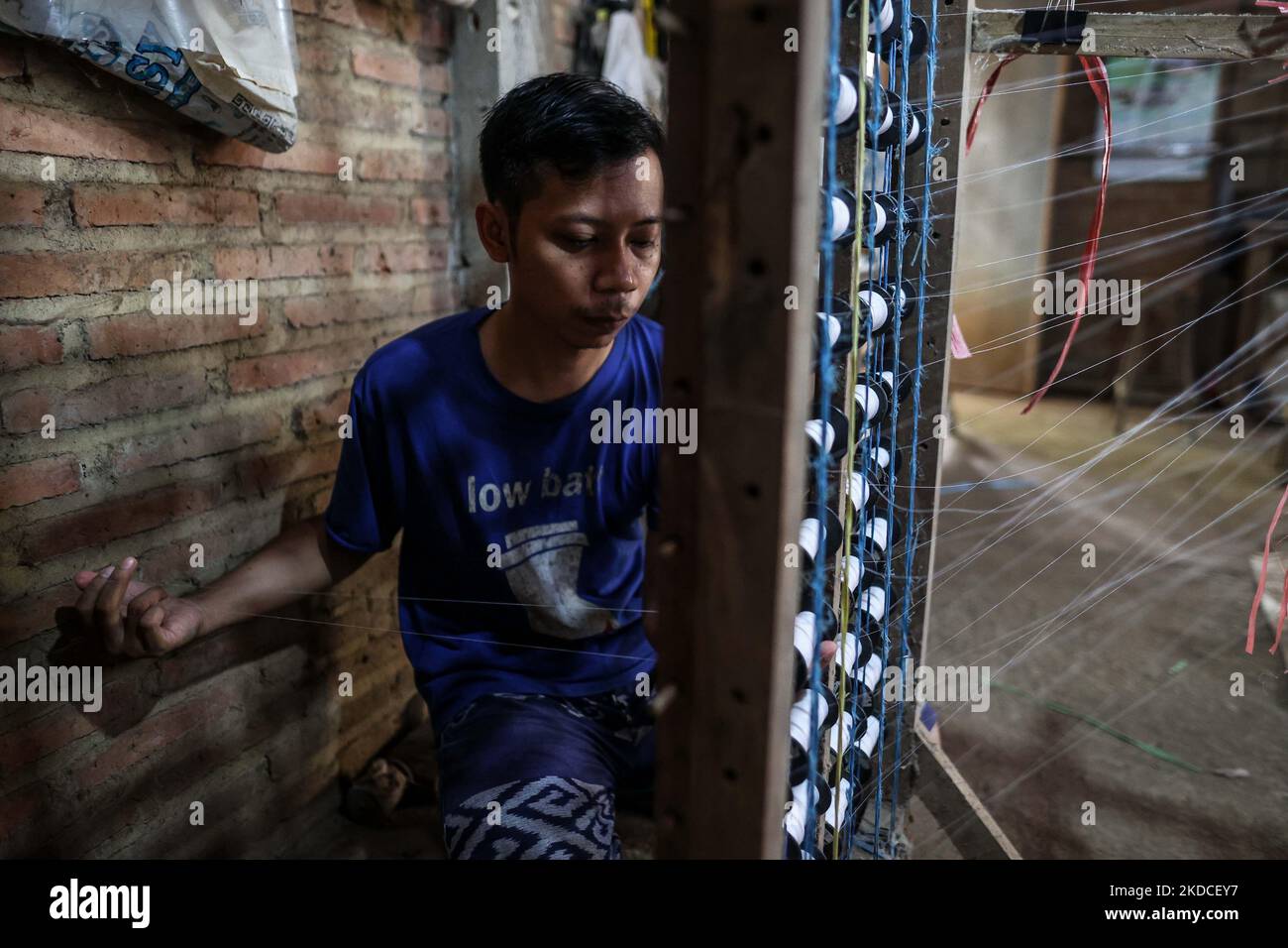 Un tisserand change une bobine de fils de soie pour la fabrication de tissus à l'atelier de tissage traditionnel au village de Troso à Jepara, province de Java centrale, Indonésie sur 21 juin 2022. Les fabricants de textiles indonésiens sont actuellement sur une voie de rétablissement, après avoir lutté contre la pandémie COVID-19 au début de 2020 jusqu'en 2022. (Photo de Garry Lotulung/NurPhoto) Banque D'Images