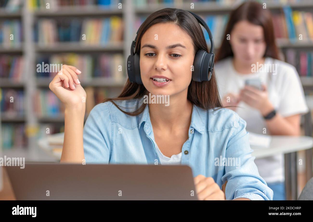 Une jeune femme travaillant dans un casque communique avec un client en ligne, consultation à l'aide d'un ordinateur portable Banque D'Images