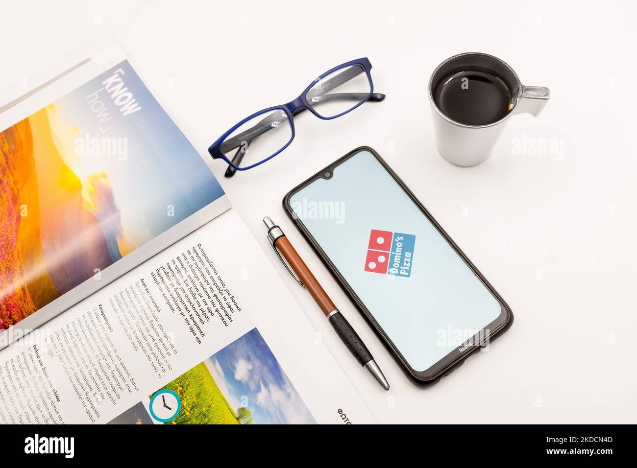 Sur cette photo, un logo pizza de Domino est affiché sur un écran de smartphone, sur un bureau à côté d’un café, d’un stylo, de lunettes et d’un magazine à Athènes, en Grèce, sur 25 juin 2022. (Photo de Nikolas Kokovovlis/NurPhoto) Banque D'Images