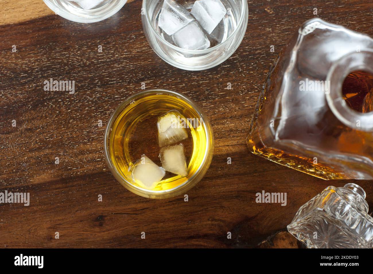 Vue en hauteur d'un verre avec chuchotement sur la glace debout le long d'un décanteur et des verres supplémentaires avec de la glace mais pas d'alcool Banque D'Images