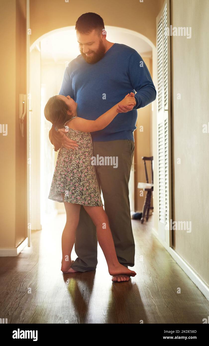 Une adorable petite fille dansant avec son père à la maison. Banque D'Images
