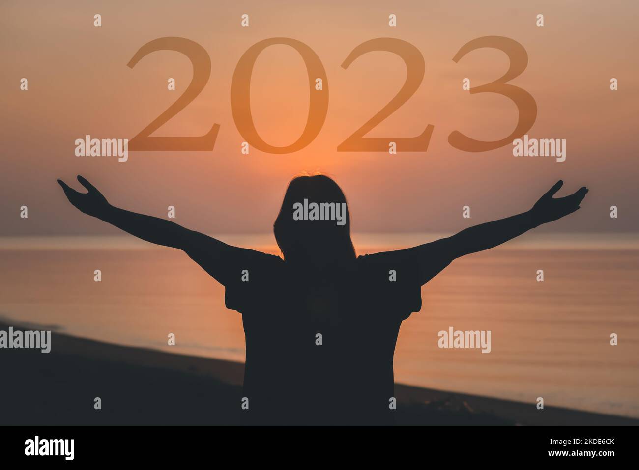 2023 concept du nouvel an heureux, la femme en santé a soulevé main tenant 2023 caractères texte au lever du soleil sur la plage. Banque D'Images