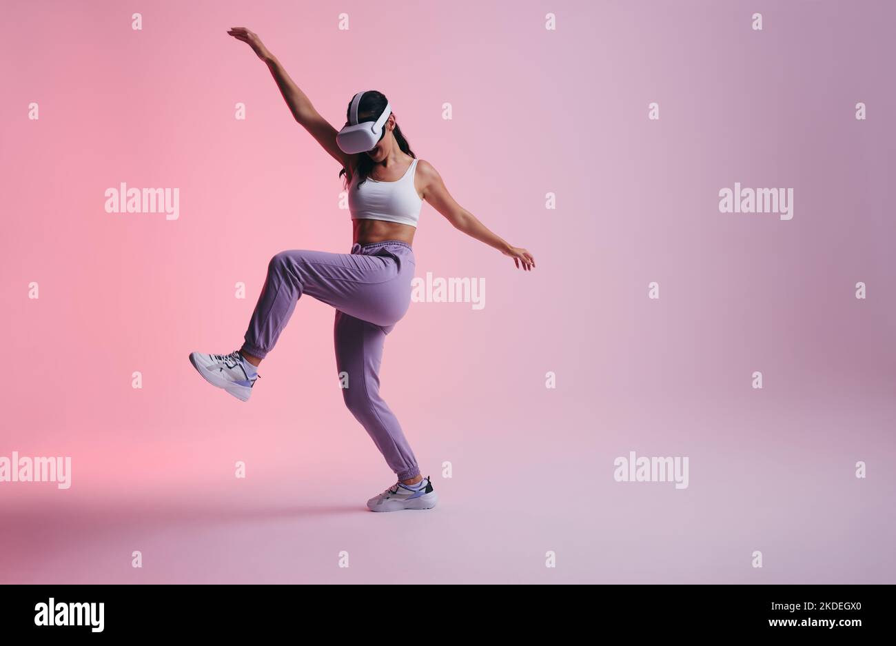 Jeune femme active dansant dans le métaverse. Une jeune femme joyeuse s'appréciant tout en portant des lunettes de réalité virtuelle. Femme s'amusant tout en expo Banque D'Images