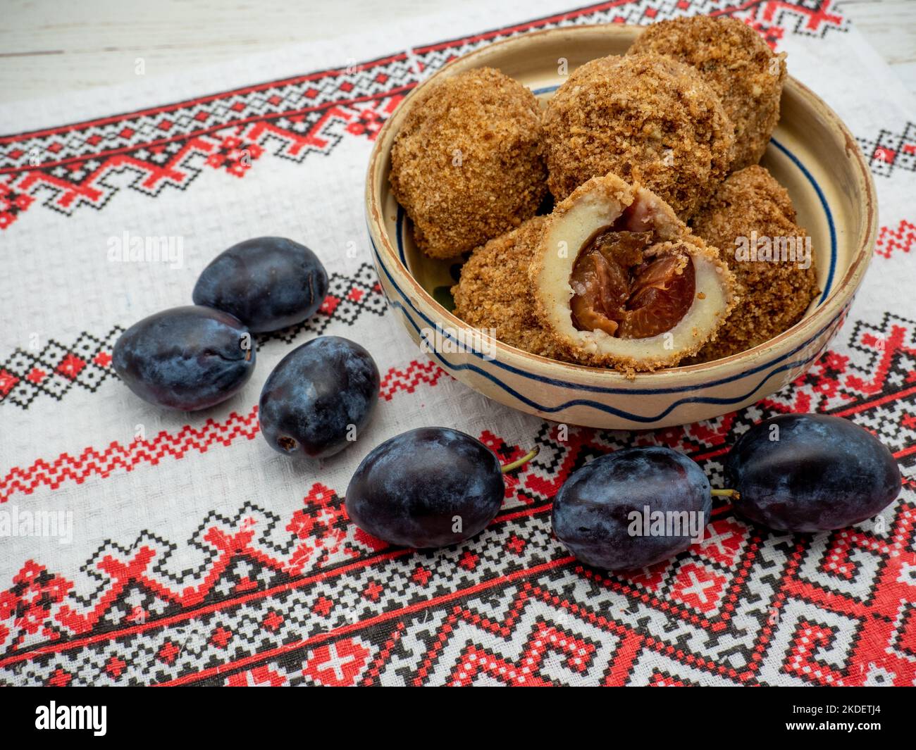 boulettes de prunes sucrées faites de pâte levain et de prunes fraîches sur un bol en argile et des prunes de côté Banque D'Images