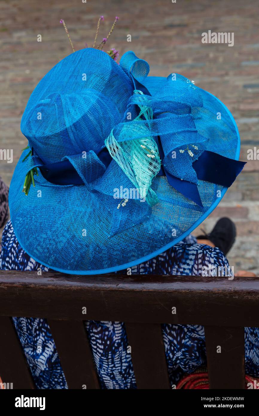 Chapeau bleu - vue arrière d'une femme assise sur un banc portant un chapeau bleu au Festival de chapeau de Bridport, Dorset, Royaume-Uni, en septembre Banque D'Images