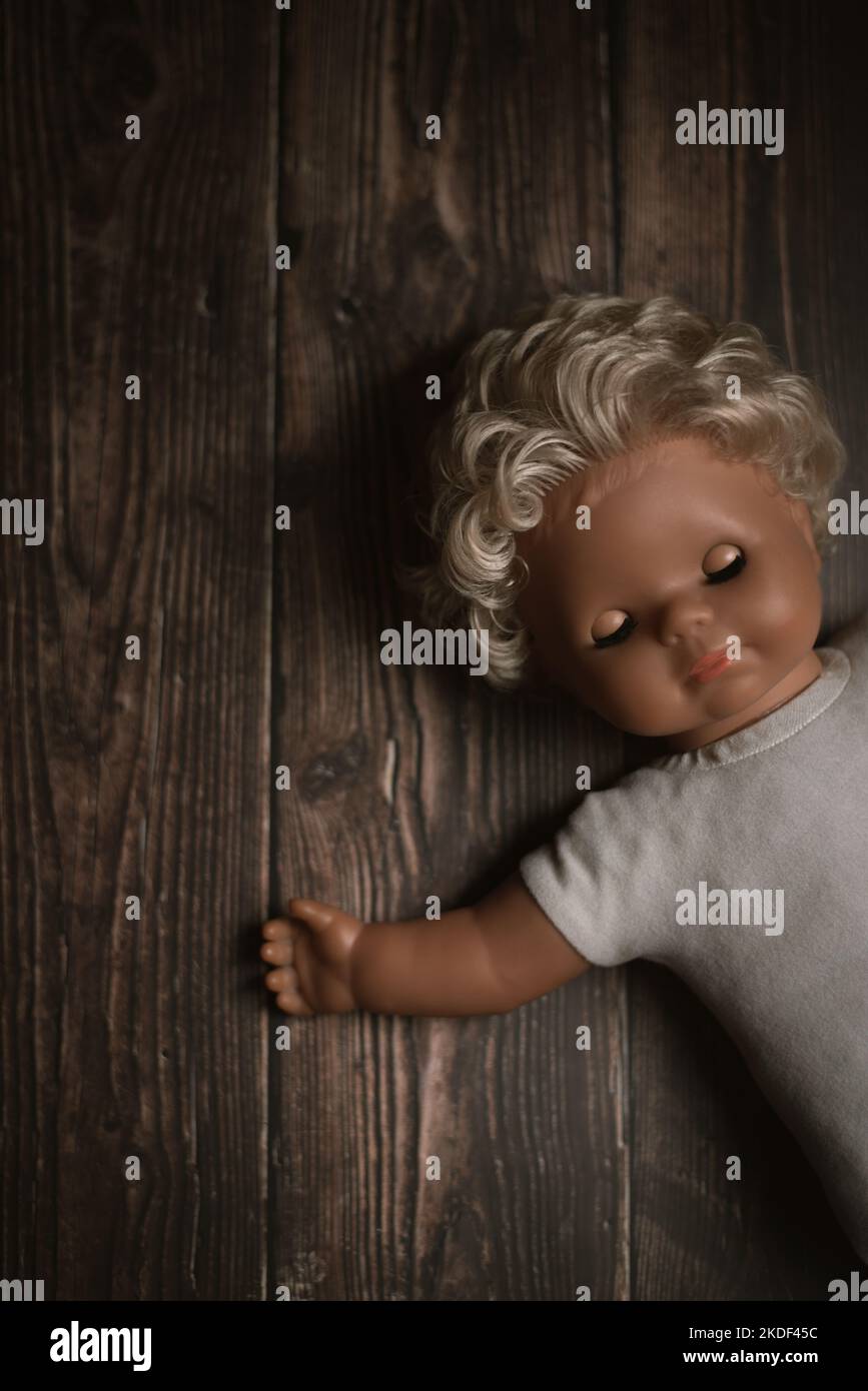 Poupée de jouet blonde ancienne perdue avec les yeux fermés couchés sur le sol Banque D'Images