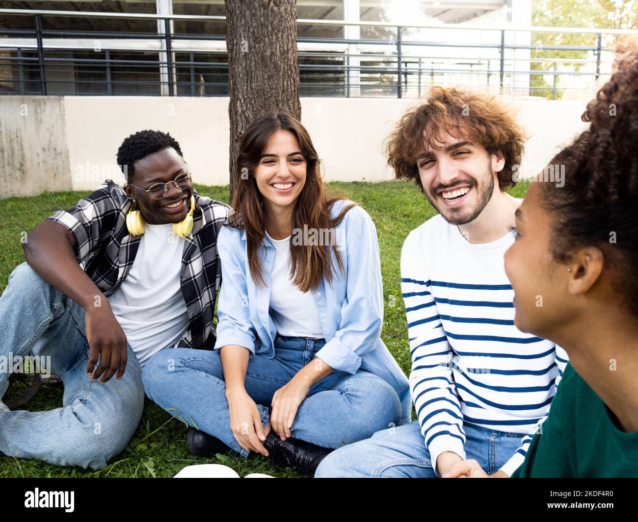 Groupe de jeunes amis divers assis sur l'herbe dans un parc ou sur le campus. Les étudiants de l'université ont un bon moment Banque D'Images