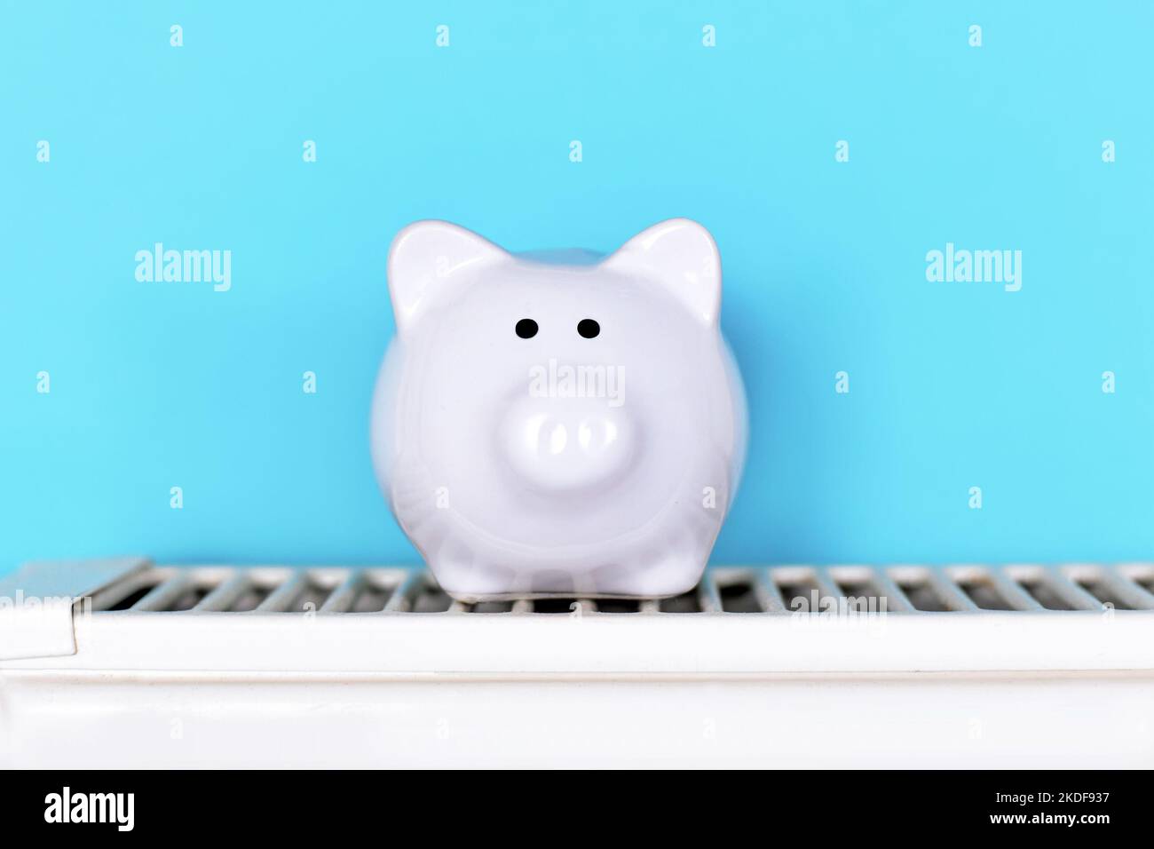Concept pour économiser de l'argent pour le gaz pour le chauffage avec banc de piggy sur radiateur devant un fond bleu Banque D'Images