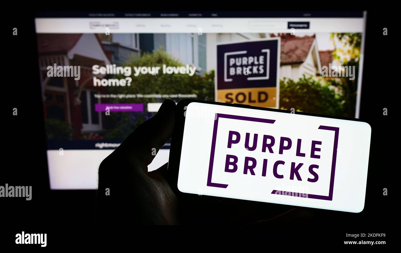 Personne tenant un smartphone avec le logo de la société immobilière Purplebricks Group plc à l'écran devant le site Web. Mise au point sur l'affichage du téléphone. Banque D'Images