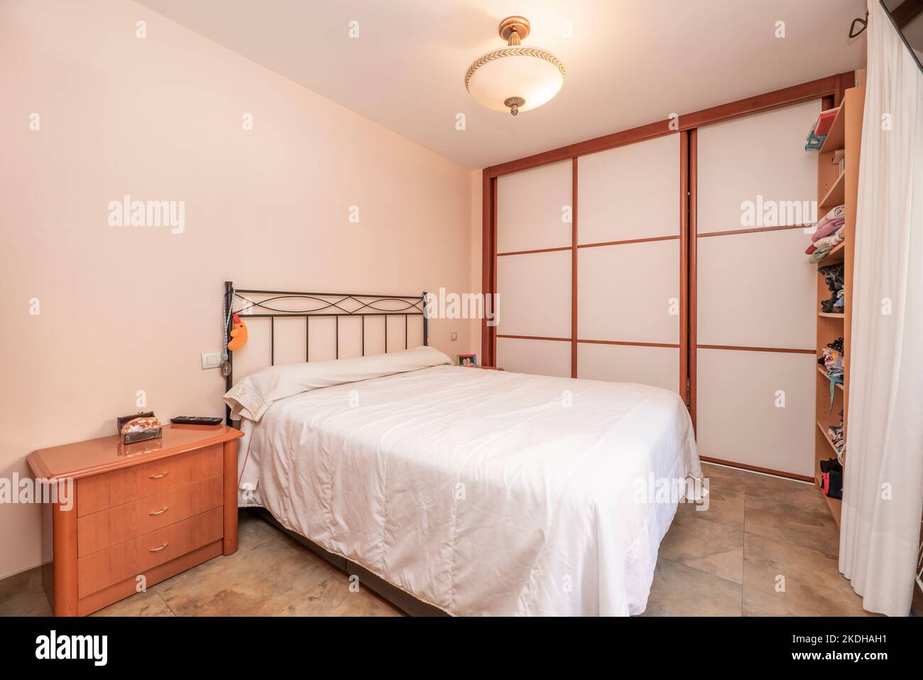 Chambre avec lit double, canapé avec portes coulissantes couvrant un mur et tables de nuit avec tiroirs assortis Banque D'Images
