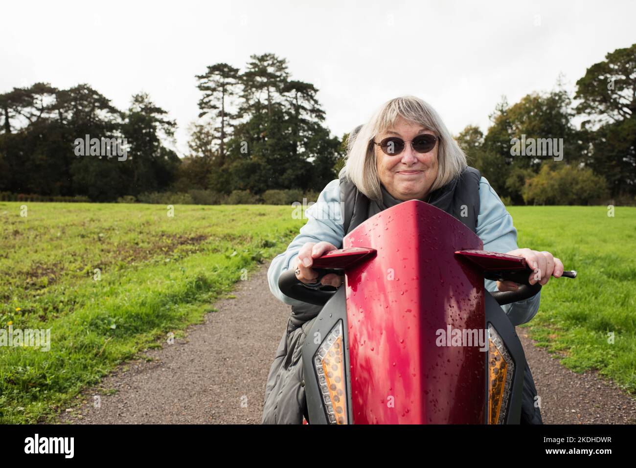 femme handicapée à la retraite sur un scooter de mobilité souriant à l'extérieur Banque D'Images