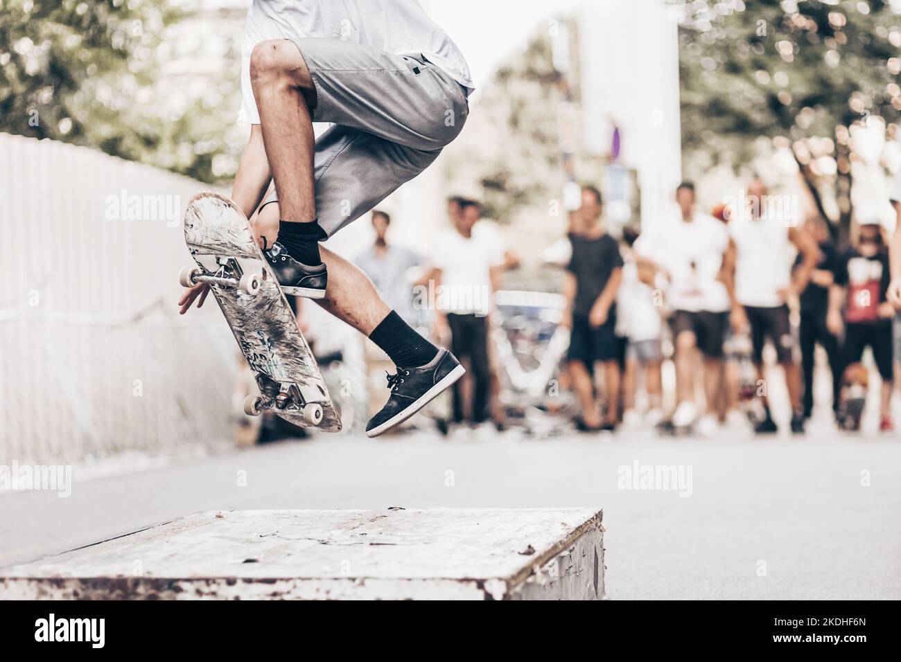 Jeune skateur professionnel de la planche à roulettes sur un objet dans la rue. Skateboarding jambes faisant affaire ollie au skate park. Groupe d'amis acclamer dans l'arrière-plan. Banque D'Images