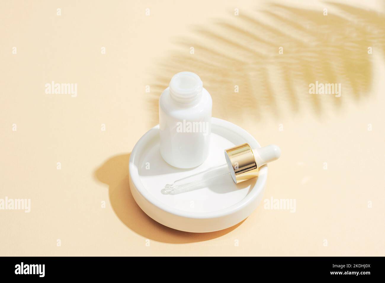 Flacon compte-gouttes blanc avec pipette et ombre à la fougères sur fond beige. Concept de cosmétiques anti-âge naturel. Gros plan. Banque D'Images