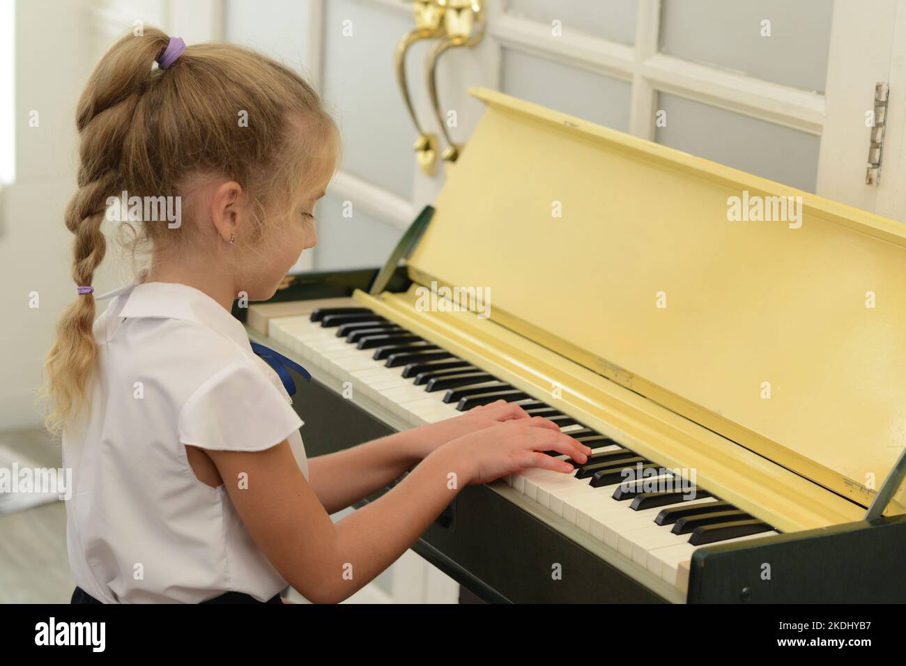 Une petite fille blanche joue le piano dans la salle, qui est une éducation  classique pour les enfants, l'apprentissage de l'art Photo Stock - Alamy