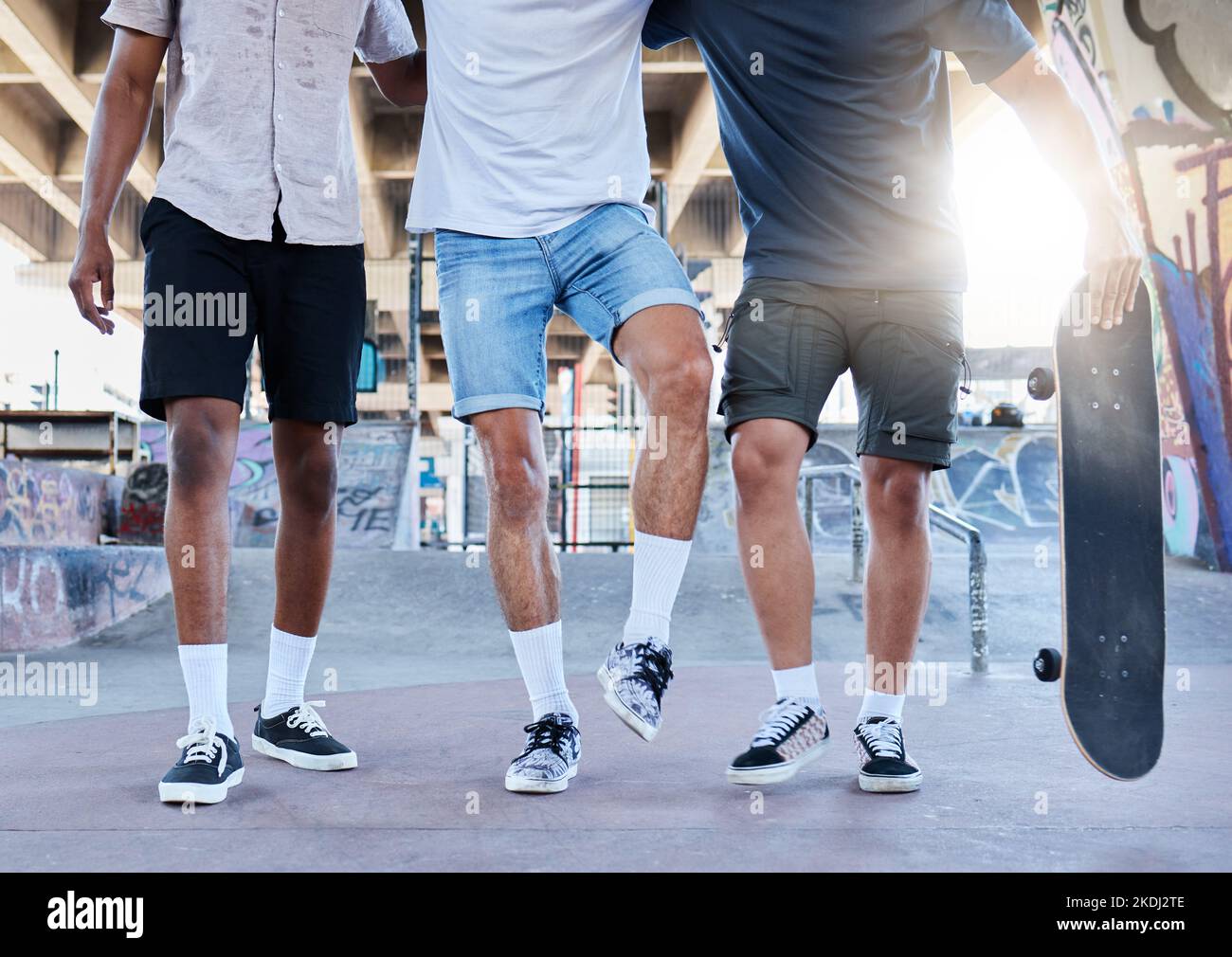 Fitness, planche à roulettes et jambes d'amis dans un parc de skate dans une ville pour l'entraînement, le sport et le plaisir d'été. Chaussures, hommes et groupe de skateboarder marchant avant Banque D'Images