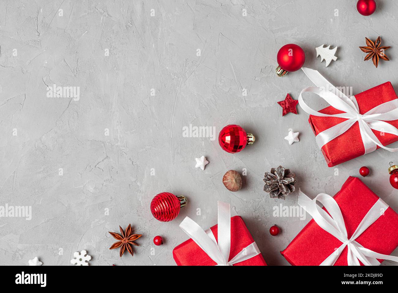 Composition de Noël. Boîtes-cadeaux rouges avec décorations de vacances, cônes de pin et noix sur fond gris. Pose à plat. Vue de dessus avec espace de copie Banque D'Images