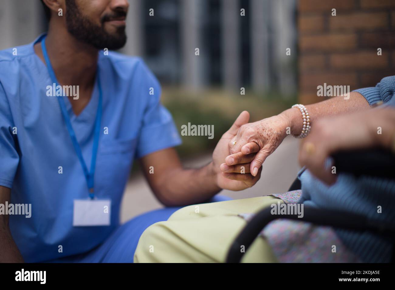 Gros plan du soignant tenant la main de son client sur un fauteuil roulant. Banque D'Images