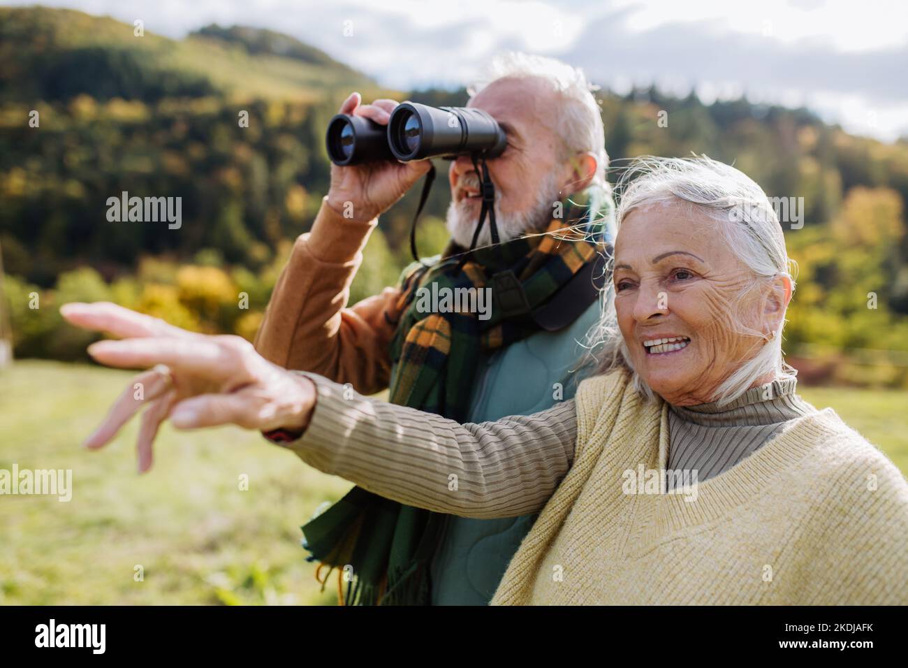 Couple senior regardant la vue à travers des jumelles lors de la marche d'automne. Banque D'Images