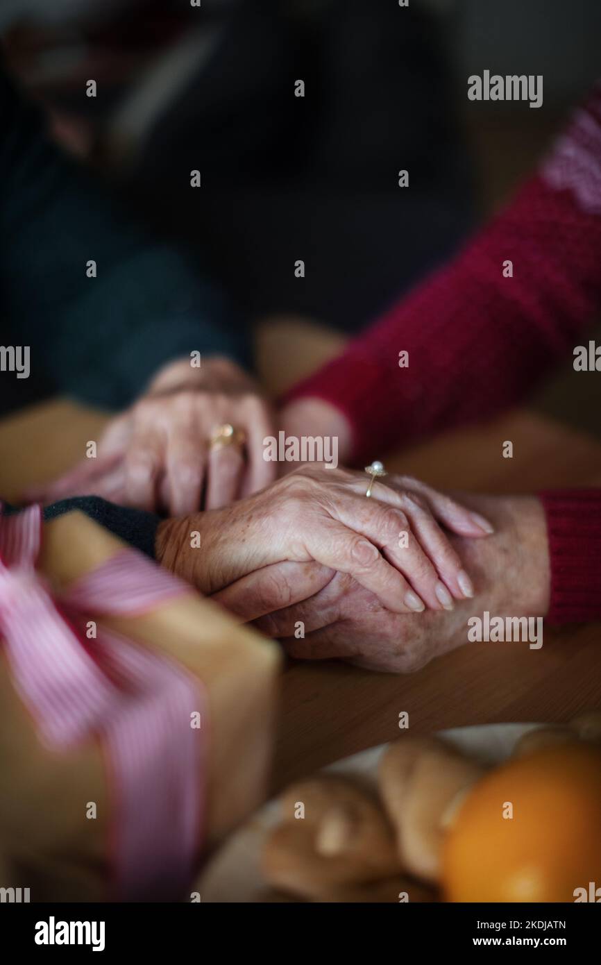 Vue en grand angle des mains de couple de personnes âgées se tenant les unes les autres, pendant Noël. Banque D'Images