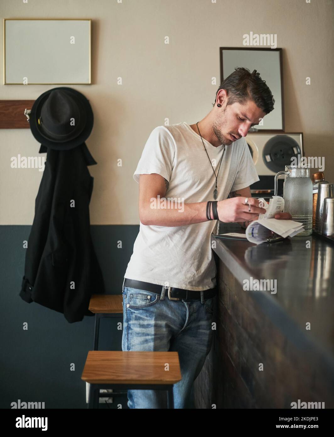 S'assurer que les chiffres sont bien additionner. Un jeune barman spécialisé prend des notes sur les reçus derrière le bar. Banque D'Images