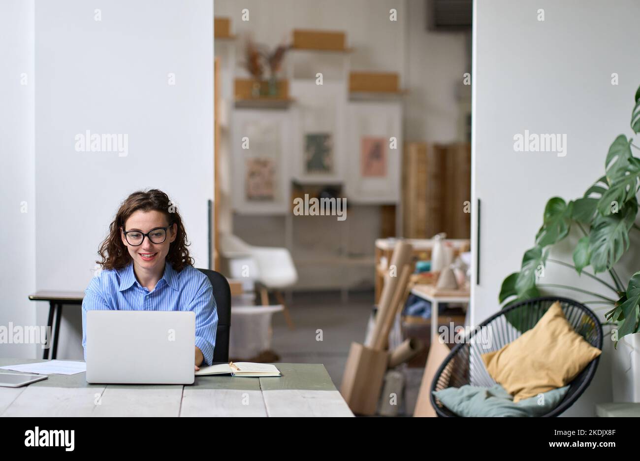 Jeune femme d'affaires souriante ou étudiante assise au bureau à l'aide d'un ordinateur portable. Banque D'Images
