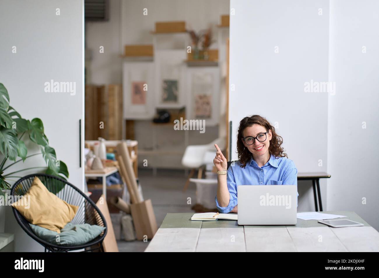 Jeune femme d'affaires heureuse ou étudiante travaillant sur un ordinateur portable pointant de côté. Banque D'Images