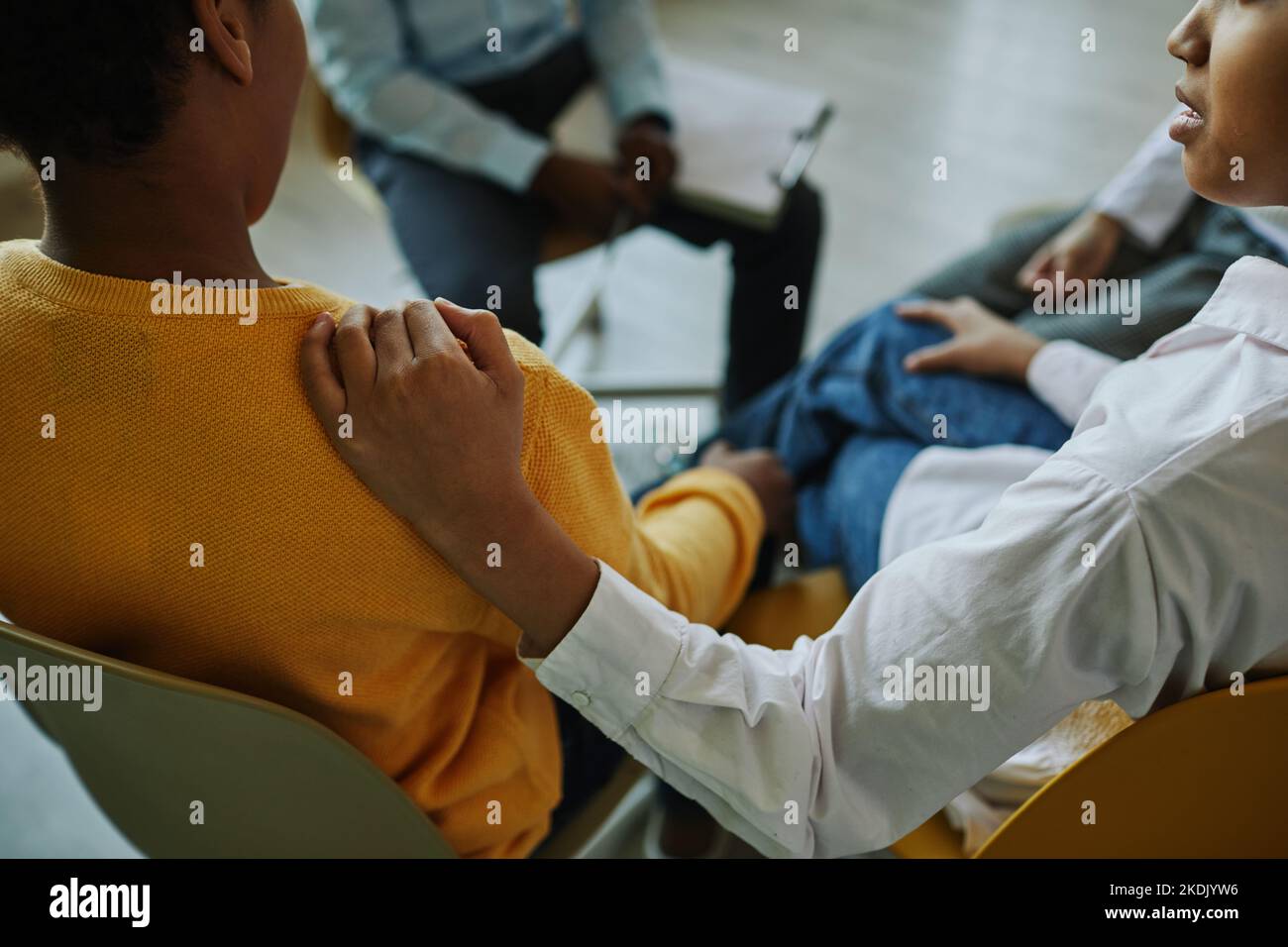 Gros plan de la main d'une écolière sur l'épaule d'un camarade classe inquiet assis parmi ses amis et psychologue et décrivant ses problèmes Banque D'Images