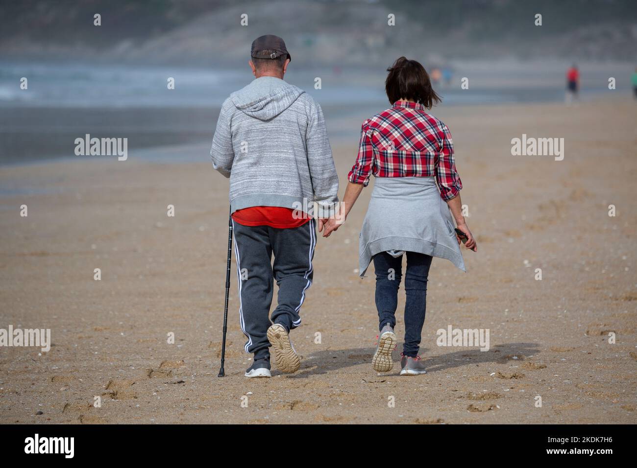 Un couple d'âge moyen marche main dans la main sur la plage d'A Lanzada, O Grove Banque D'Images